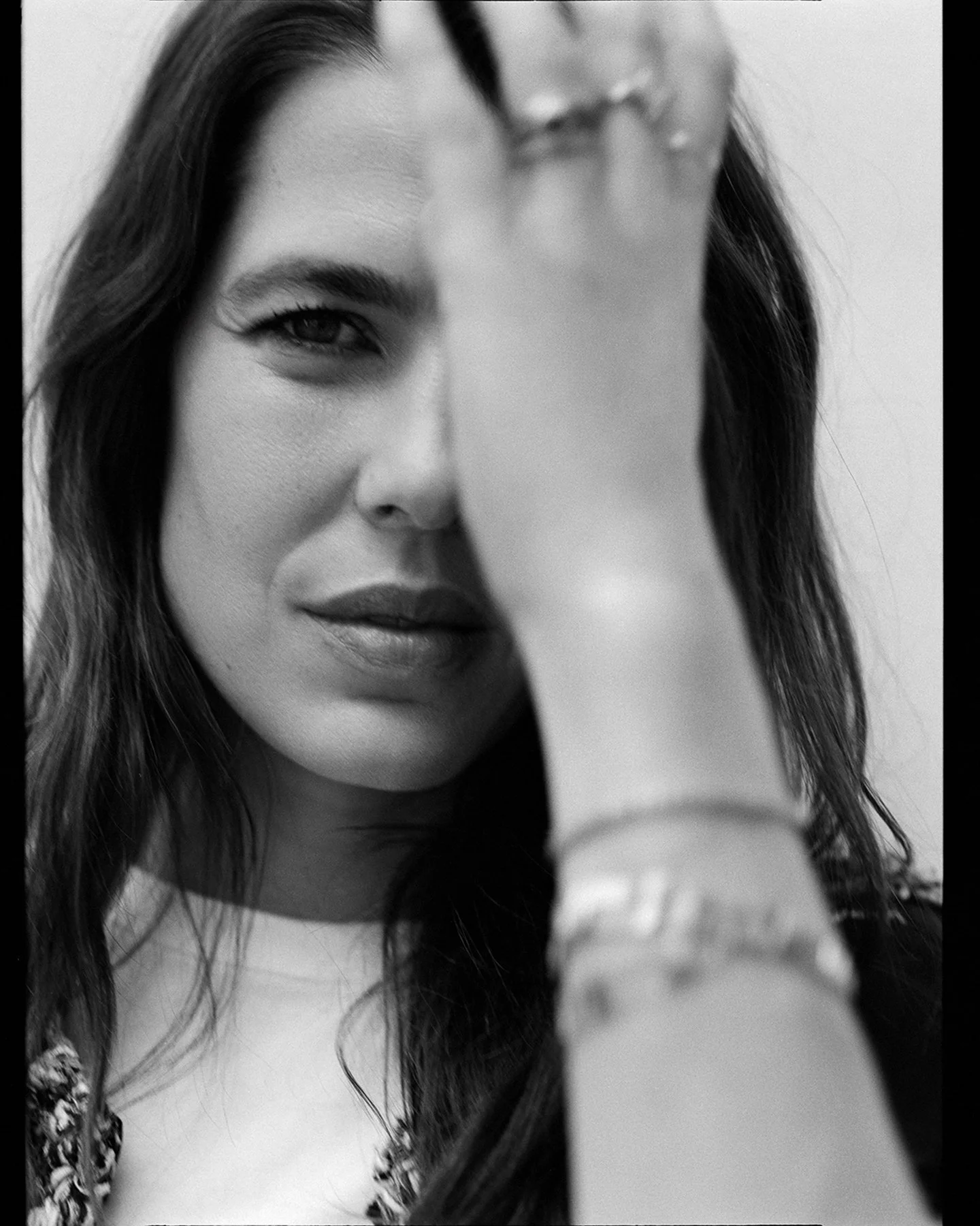  Black-and-white portrait of Charlotte Casiraghi with one hand raised beside her face, photographed by Sean Thomas for d la Repubblica. Chanel Beauty, makeup by Lili Choi and hair by Thibaud Salducci. 