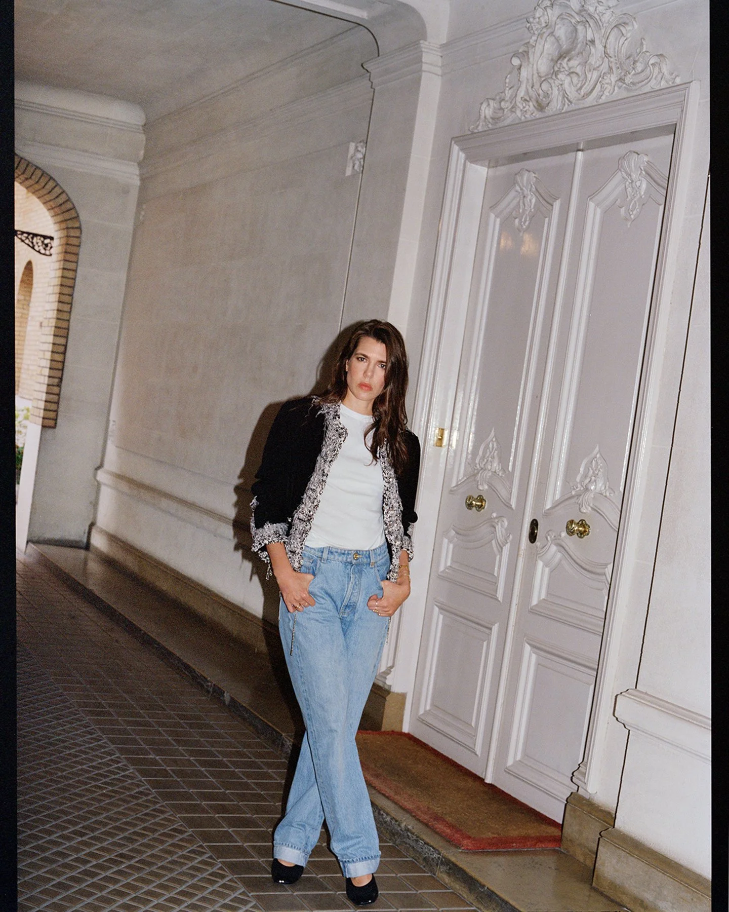  Full-length fashion portrait of Charlotte Casiraghi standing in an ornate interior, wearing a dark jacket and light trousers. Photographed by Sean Thomas for d la Repubblica, with Chanel fashion by Matthieu Blazy. 