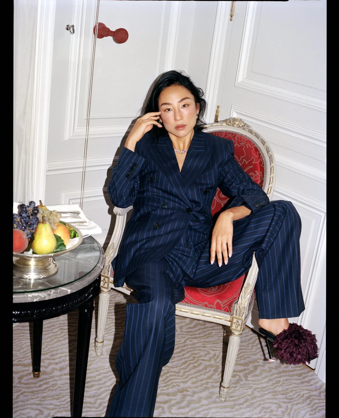  Greta Lee in a navy pinstripe suit and jewelry, photographed by Sean Thomas for Sotheby’s Magazine and styled by Geraldine Saglio. 