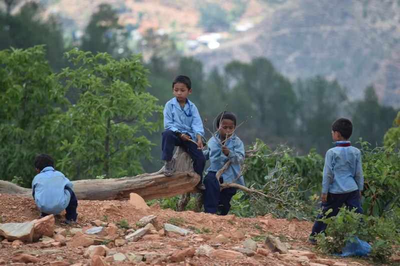 A group of boys playing on the edge of the mountain during their lunch break.