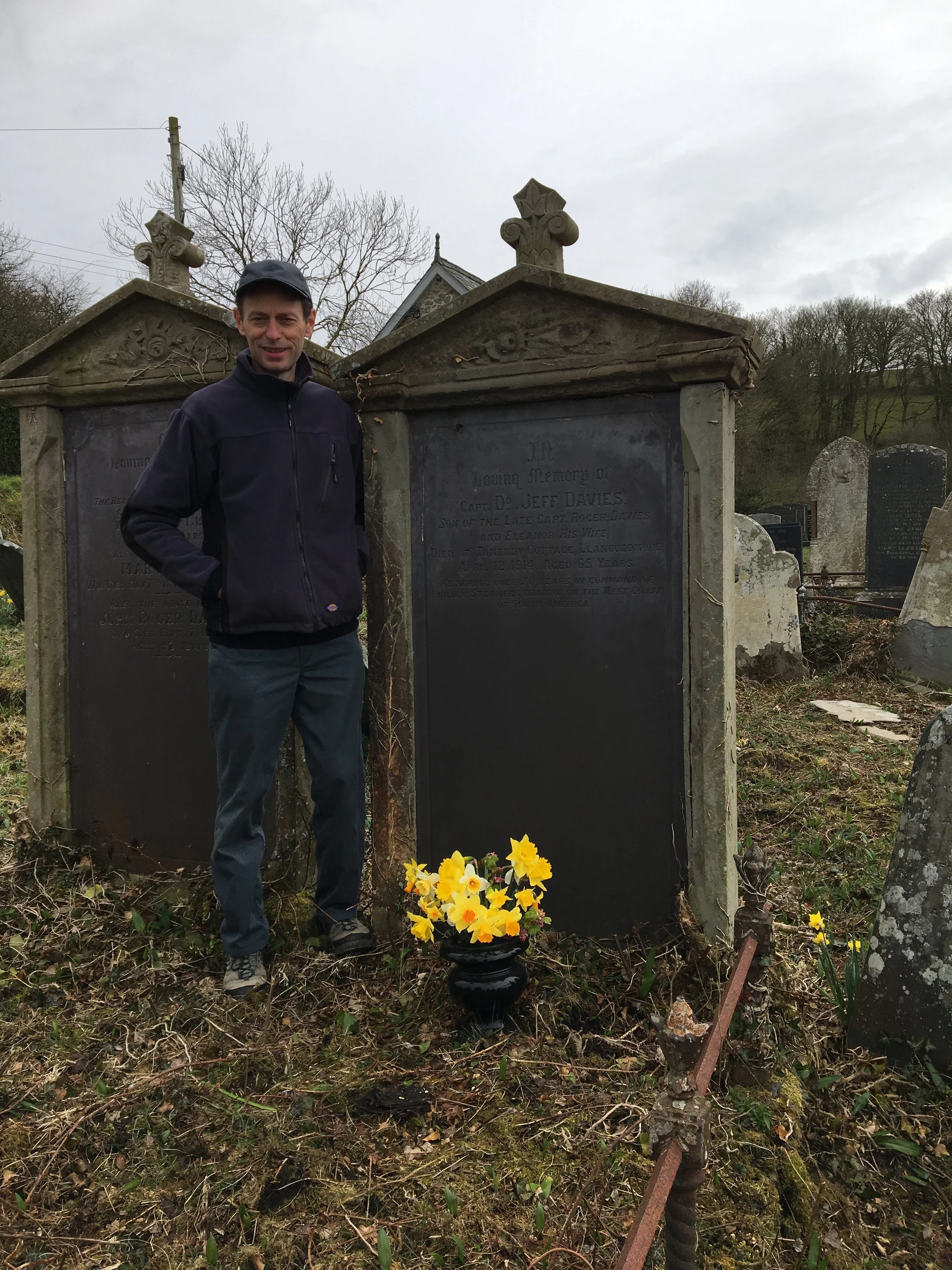 Fy mrawd, Gareth Davies, yn sefyll ar bwys y bedd. Ni yw'r bobl gyntaf i osod blodau ar ei fedd ers blynyddoedd maith rwy'n credu. My brother, Gareth Davies, by the graveside. I suspect we are the first people to lay flowers on his grave for a very long time.