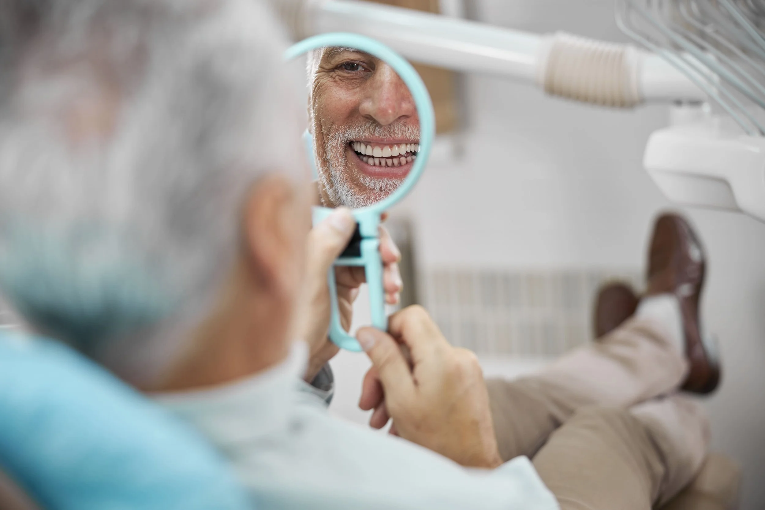 Paciente mirando en el espejo el resultado de la colocación de implantes dentales