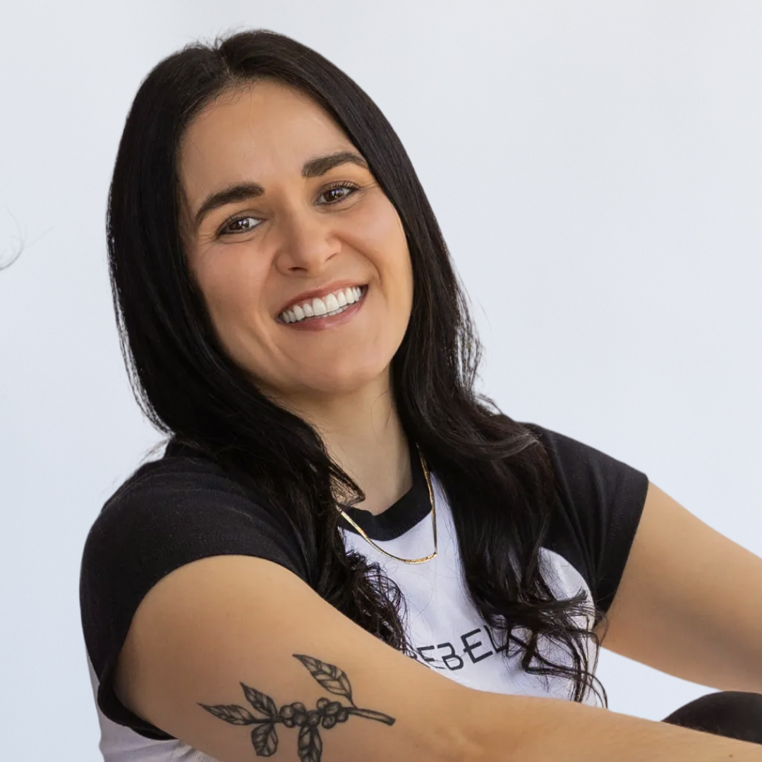 Woman with dark hair lifting a dumbbell in a gym or fitness studio.