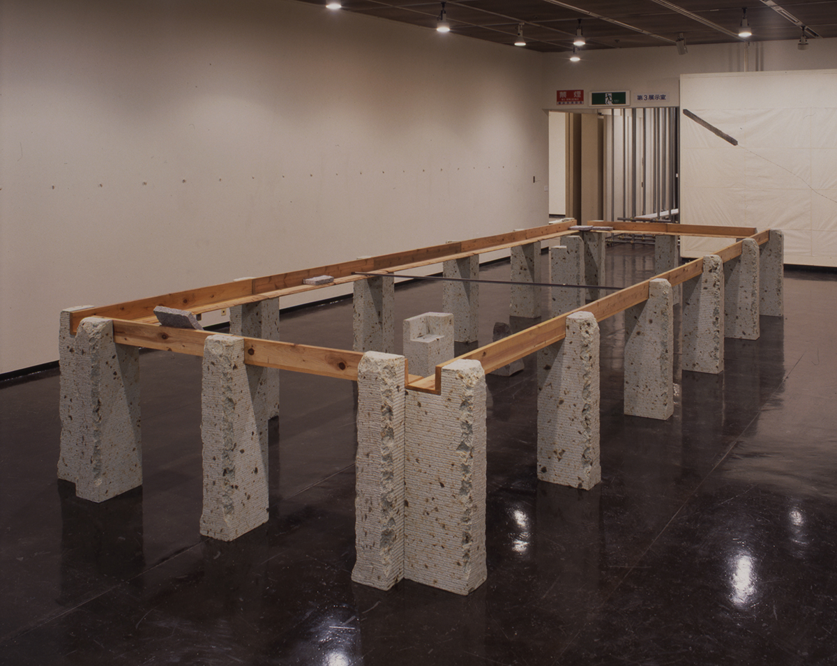 Supported Surrounding , 1987 縁辺仕帯 ( Enpen Shitai ) Wood planks, stone, aluminum 41 3/8 x 103 3/4 x 305 1/2 inches overall Installation view, Kishio Suga , Kanagawa Prefectural Gallery, Yokohama, 1998 Courtesy Kanagawa Prefectural Gallery, Yokohama