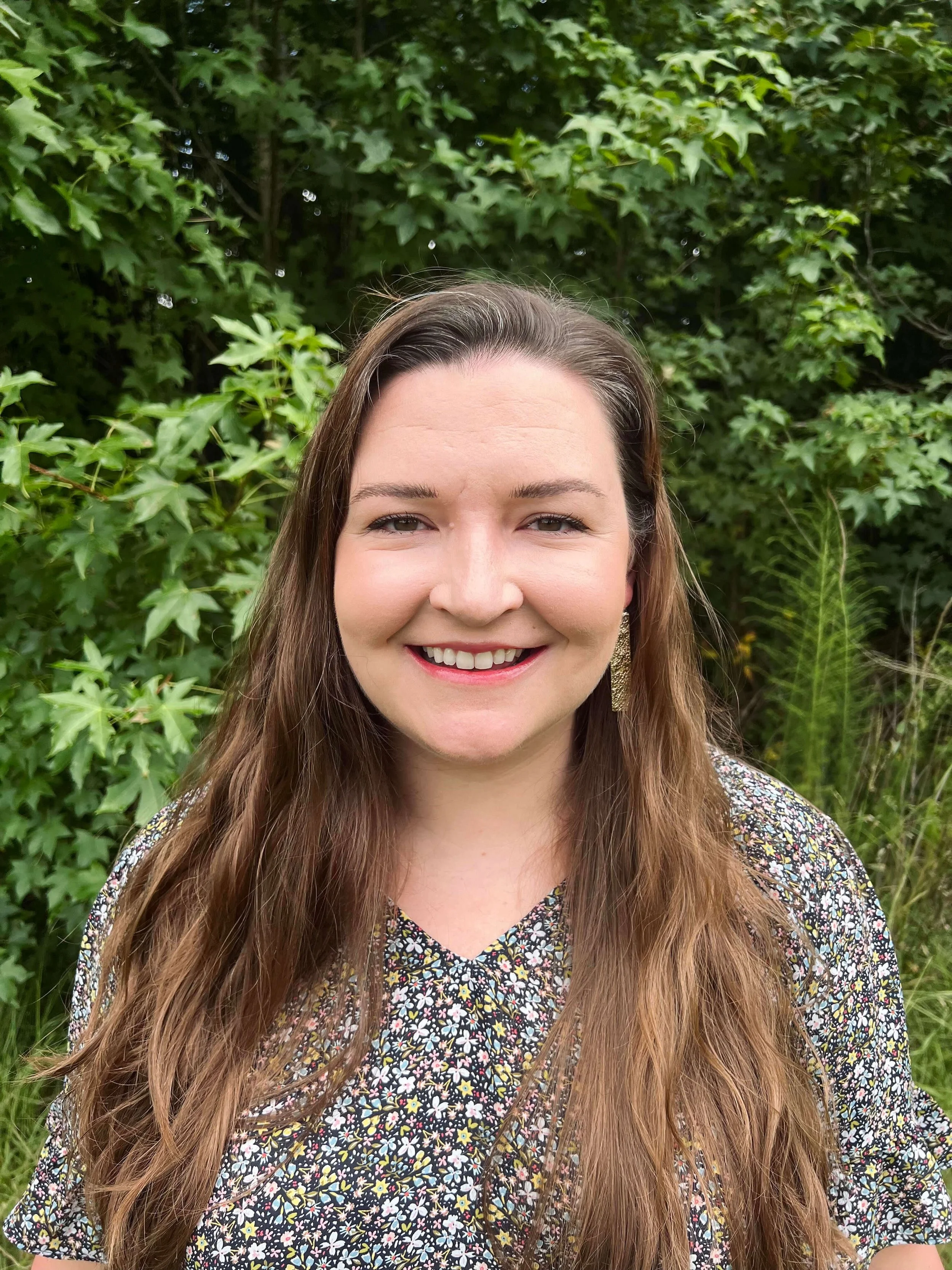 Megan Shope has long brown hair, brown eyes, a floral shirt. She is a HAES focused psychologist