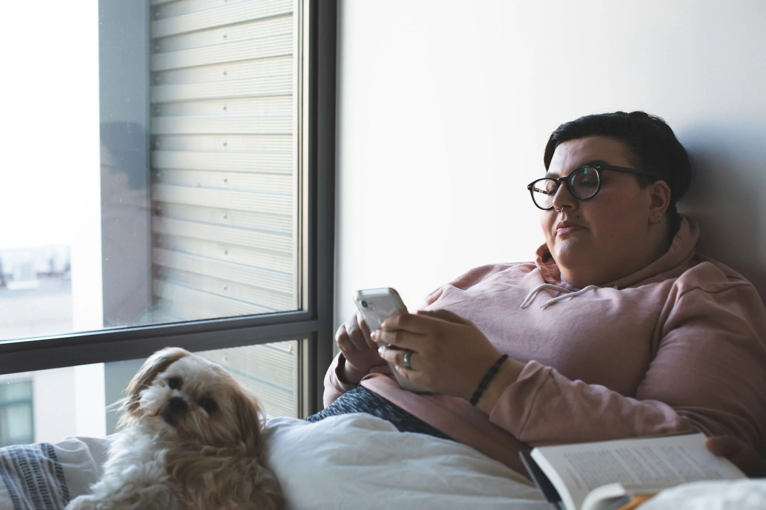 Person laying in bed scrolling on their phone. Represents trauma therapy.