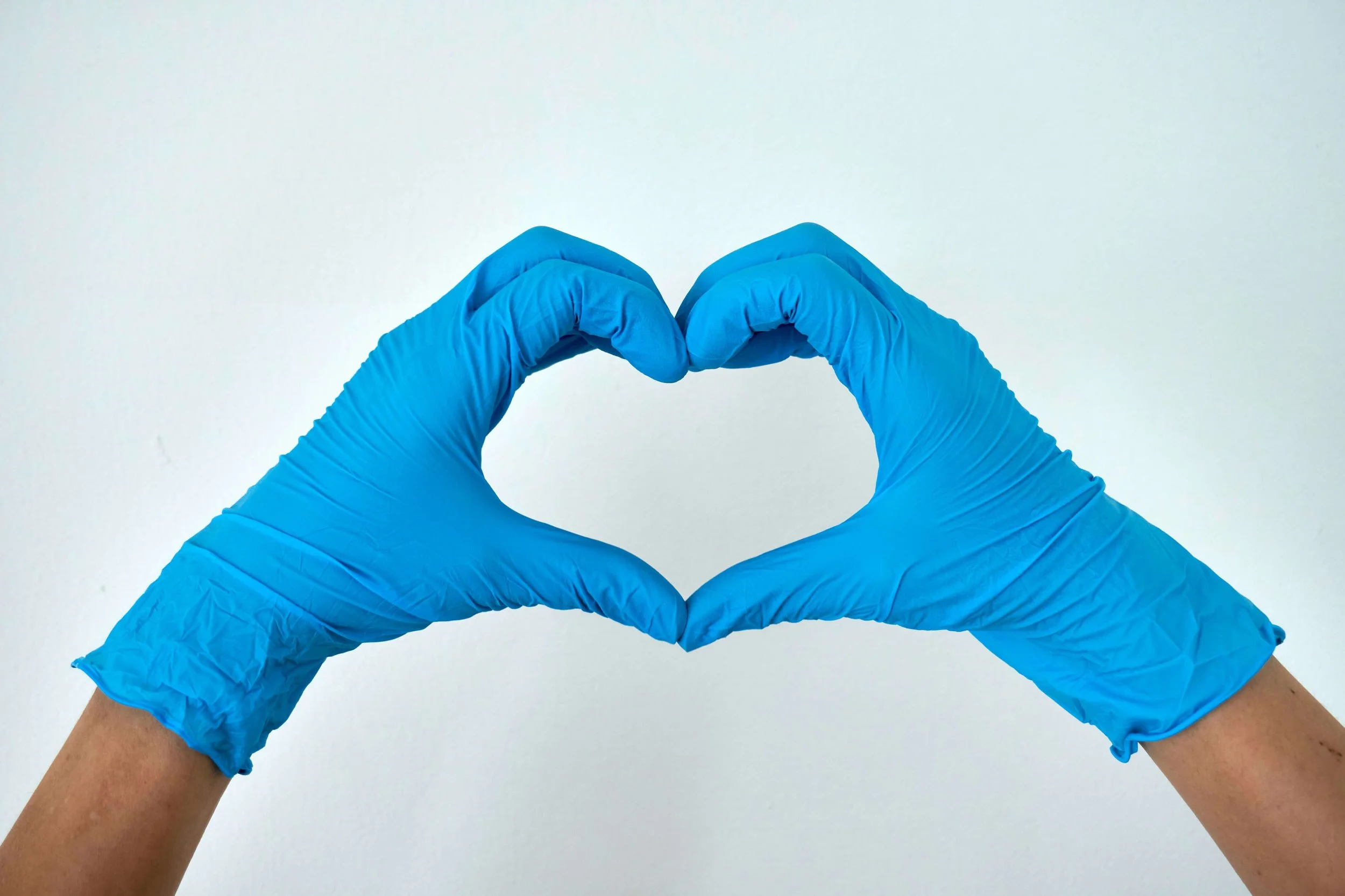 Hands wearing blue medical gloves making the shape of a heart. Represents medical trauma Seattle.