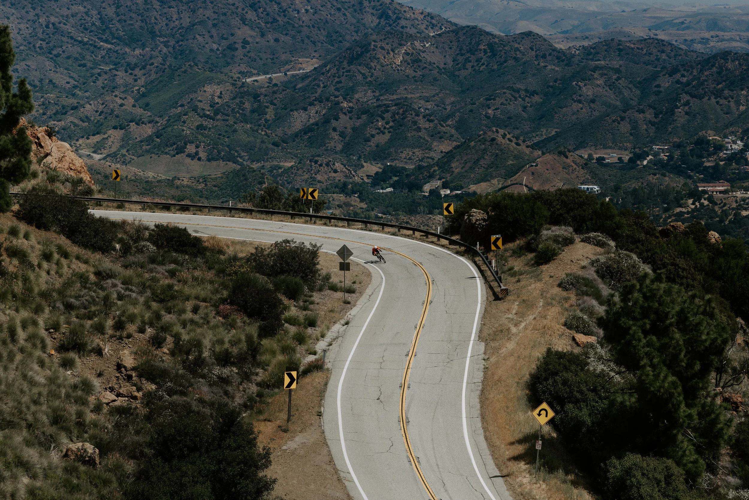 A cyclist descending a winding road through the Santa Monica Mountains