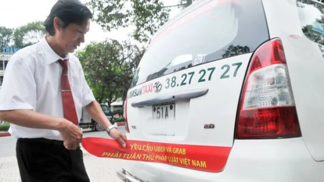 Tài xế gỡ yêu cầu dán đằng sau xe taxi. Ảnh: Cao Thăng&nbsp; &nbsp;