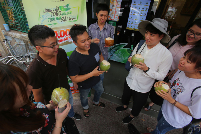  Các bạn trẻ thích thú giải nhiệt với những trái dừa được tặng miễn phí từ máy bán dừa tự động trên đường Hồ Tùng Mậu, quận 1   