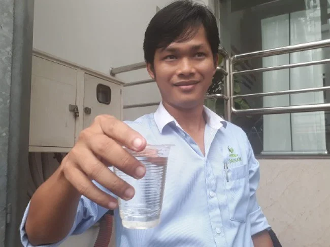 Th.s Ngô Quang Hiếu cầm trên tay ly nước thải ra môi trường sau khi qua xử lý tại Viện gút TP.HCM. Ảnh: Hà Thế An.