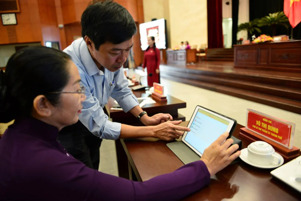 Cuộc họp bị ngắt quãng nhiều lần do nhân viên kỹ thuật phải hỗ trợ đại biểu biểu quyết qua ipad. Ảnh: Lê Quân.