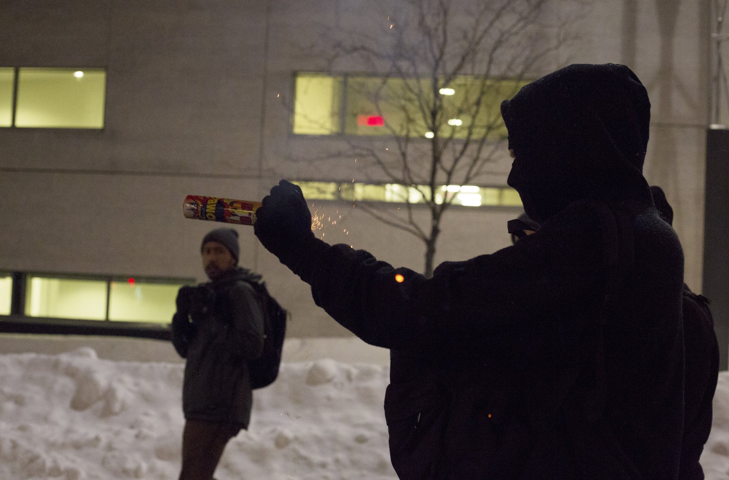  Protester in the process of shooting a firework at Montreal Police (SPVM) during a demonstration against police brutality. March 15 2017.  