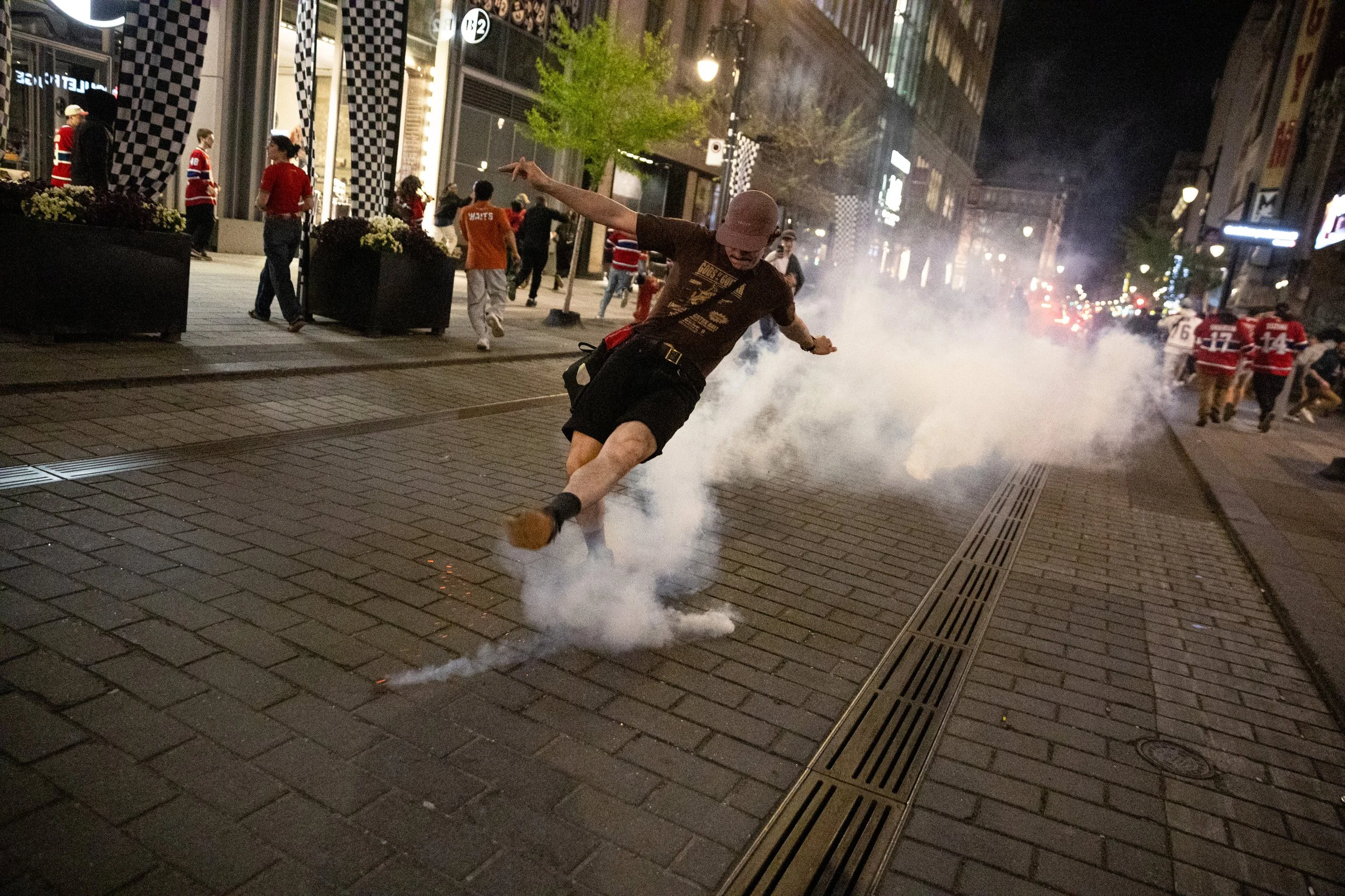  Montreal Canadiens fan kicking a tear gas pellet away from a crowd after SPVM riot police attacked celebrating partisans following the team’s second round playoff win against the Buffalo Sabres. Downtown Montreal. May 18, 2026.  