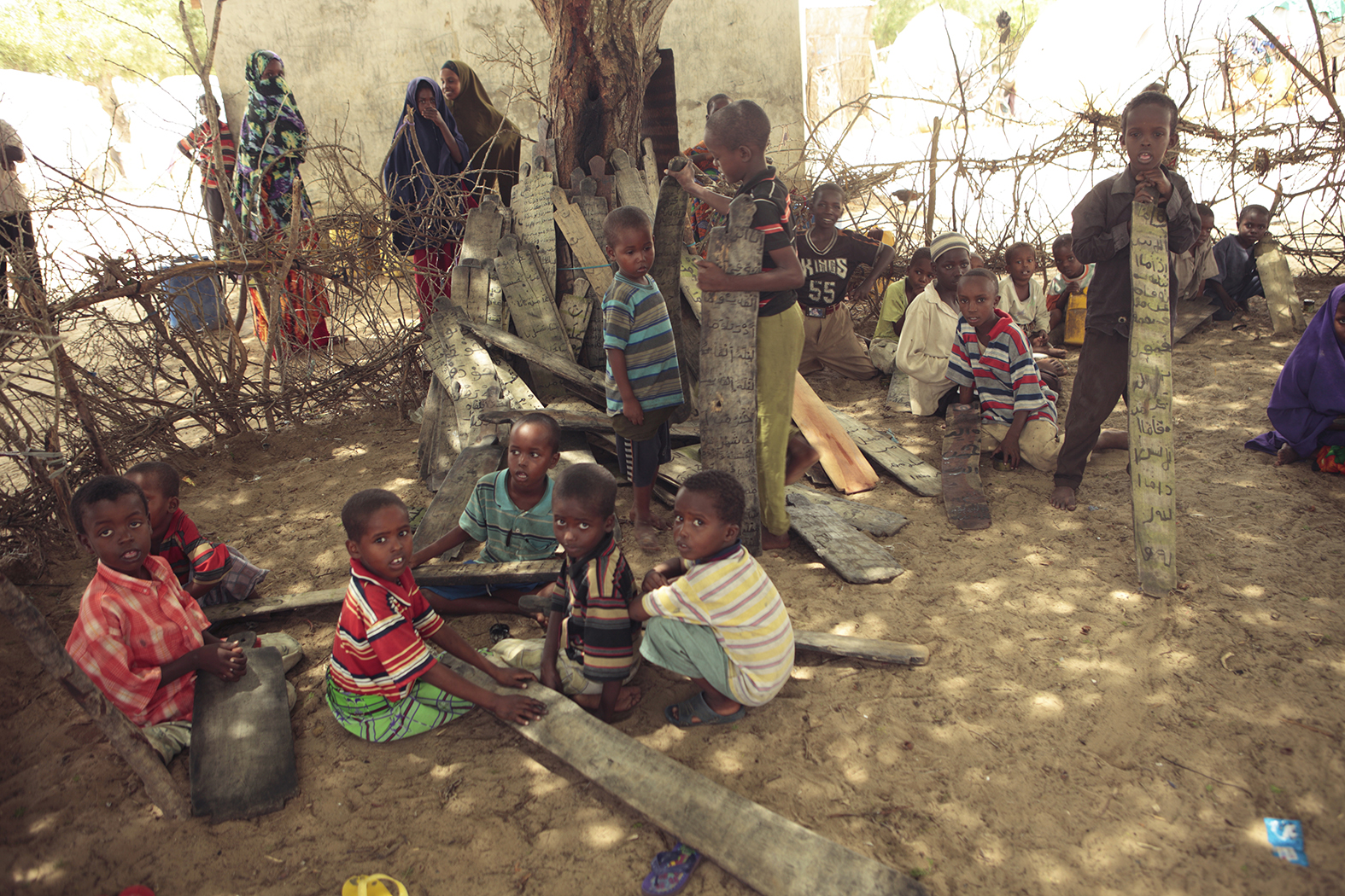   Students write with charcoal on wood panels at a Koranic school  