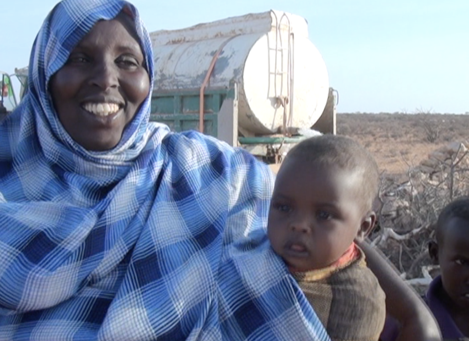   A villager and her baby are happy about the water delivery  