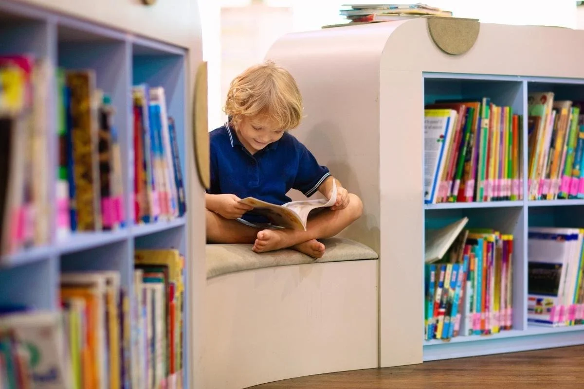 Kindergartener reading a book independently to practice early reading and phonics skills.