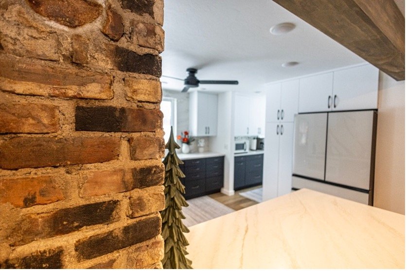 A beautiful custom home interior in Chetek, WI, featuring a rustic reclaimed brick pillar and a modern open-concept kitchen by Schmidt Construction.