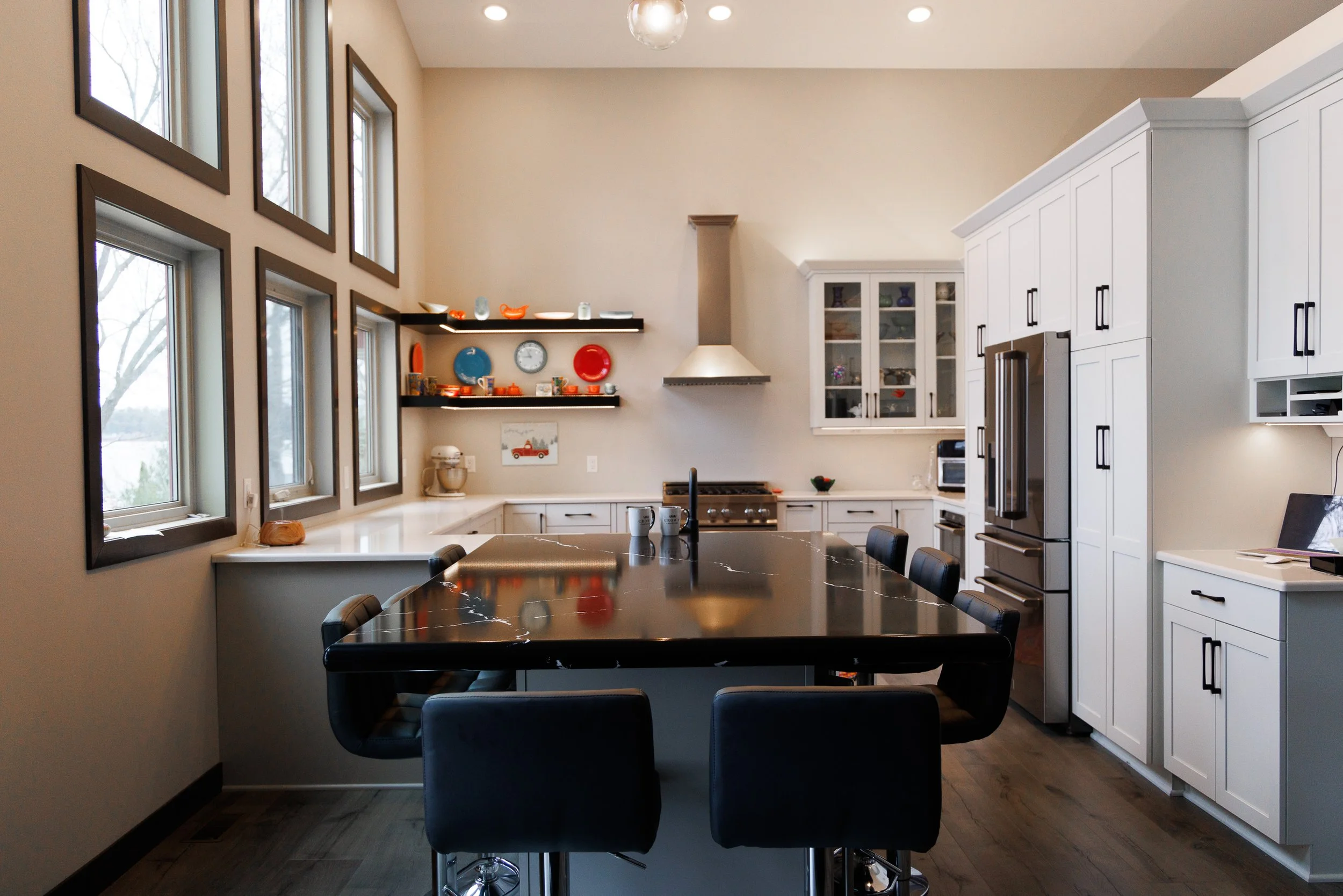 Modern custom kitchen featuring a black waterfall island, white cabinetry, and high-end finishes by Schmidt Construction in Chetek, Wisconsin.