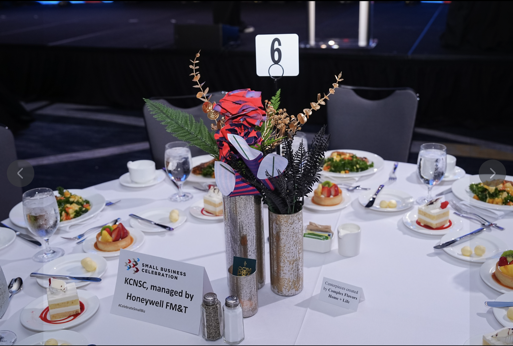 Finished fabric floral centerpiece in metallic vases on a formal banquet table.