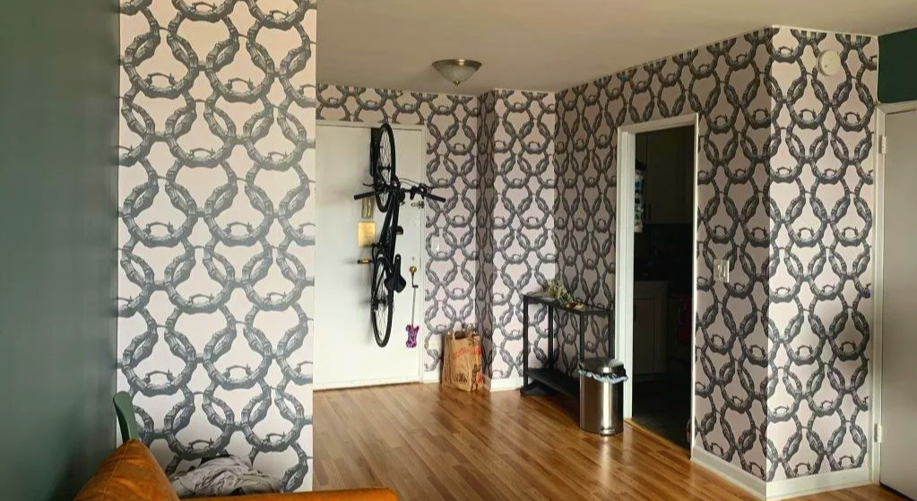 Close-up of patterned wallpaper featuring an interlocking chain design in black on a neutral background.
