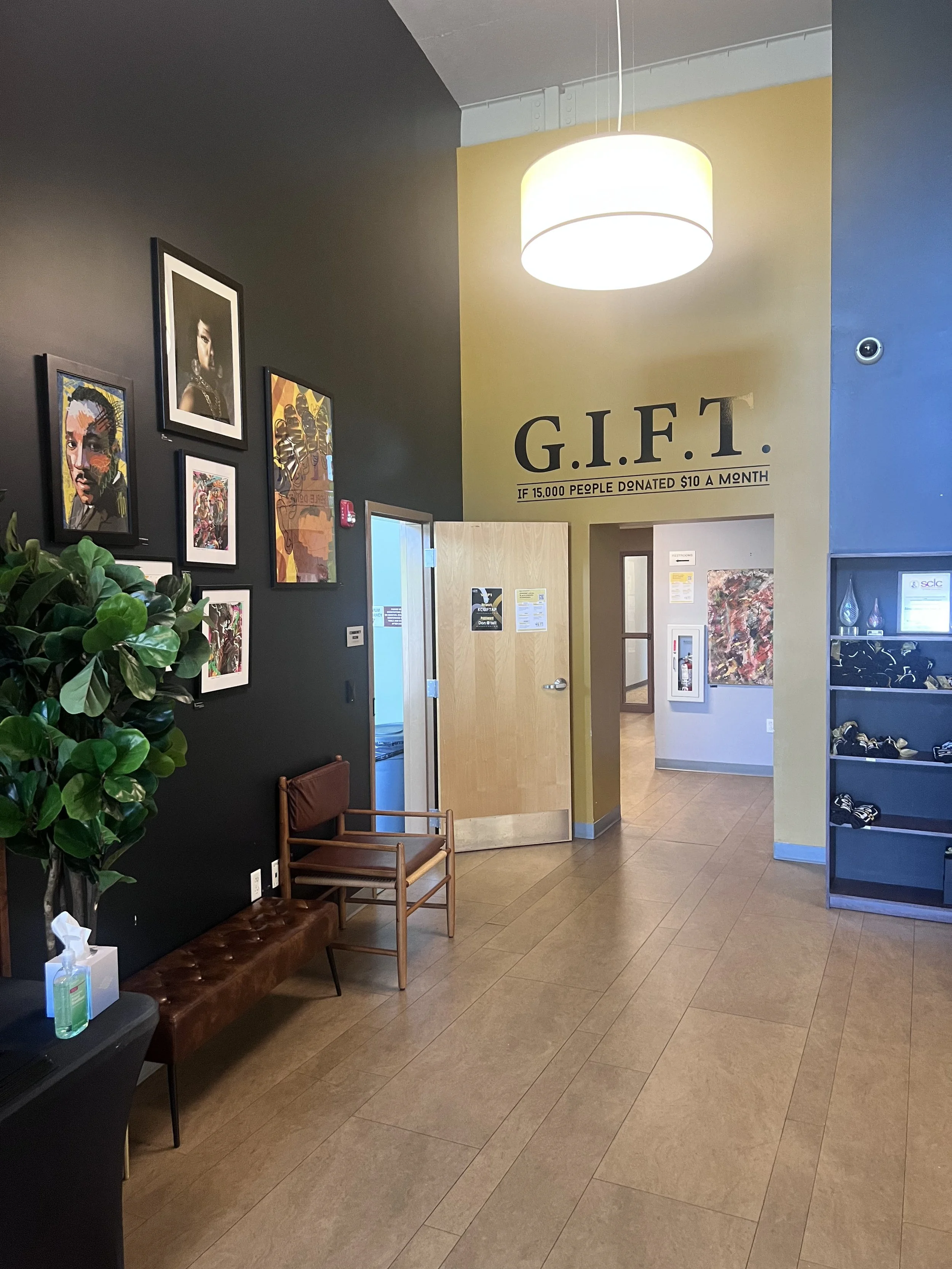Transformed KC G.I.F.T. entryway featuring gallery wall artwork, warm wood tones, and open layout leading into the space, creating a welcoming and community-centered environment.