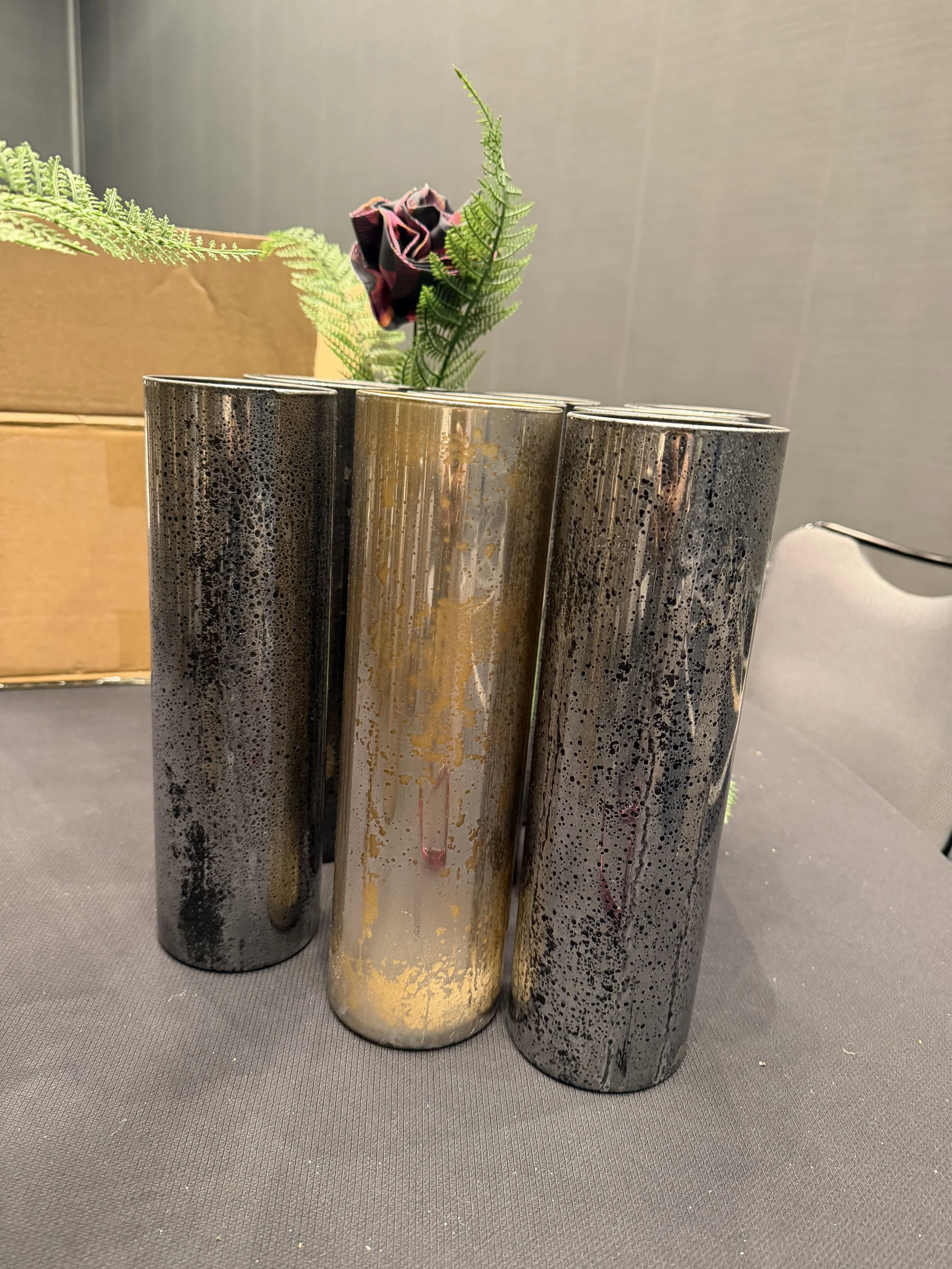Custom clear acrylic vases spray-painted with speckled gold and silver metallic finishes for a handcrafted event centerpiece.