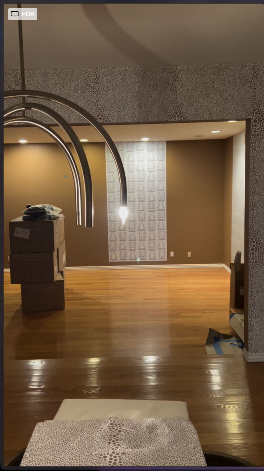 Custom wallpaper installation in progress in the Issa Rae Airbnb dining area, showing large wall sections and modern pendant lighting.