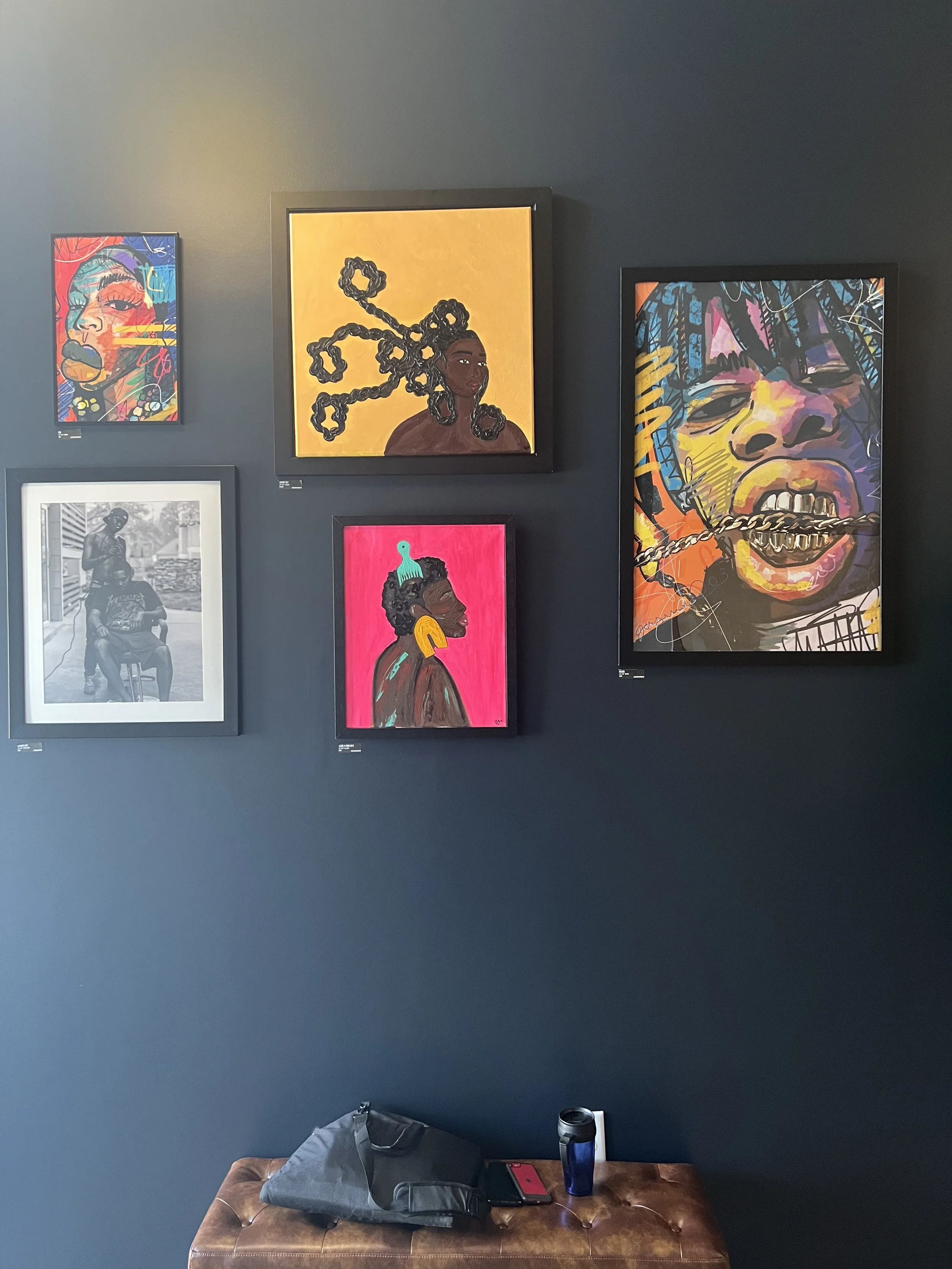Curated gallery wall at KC G.I.F.T. featuring vibrant portrait artwork by local artists, creating a cultural and community-driven visual display.
