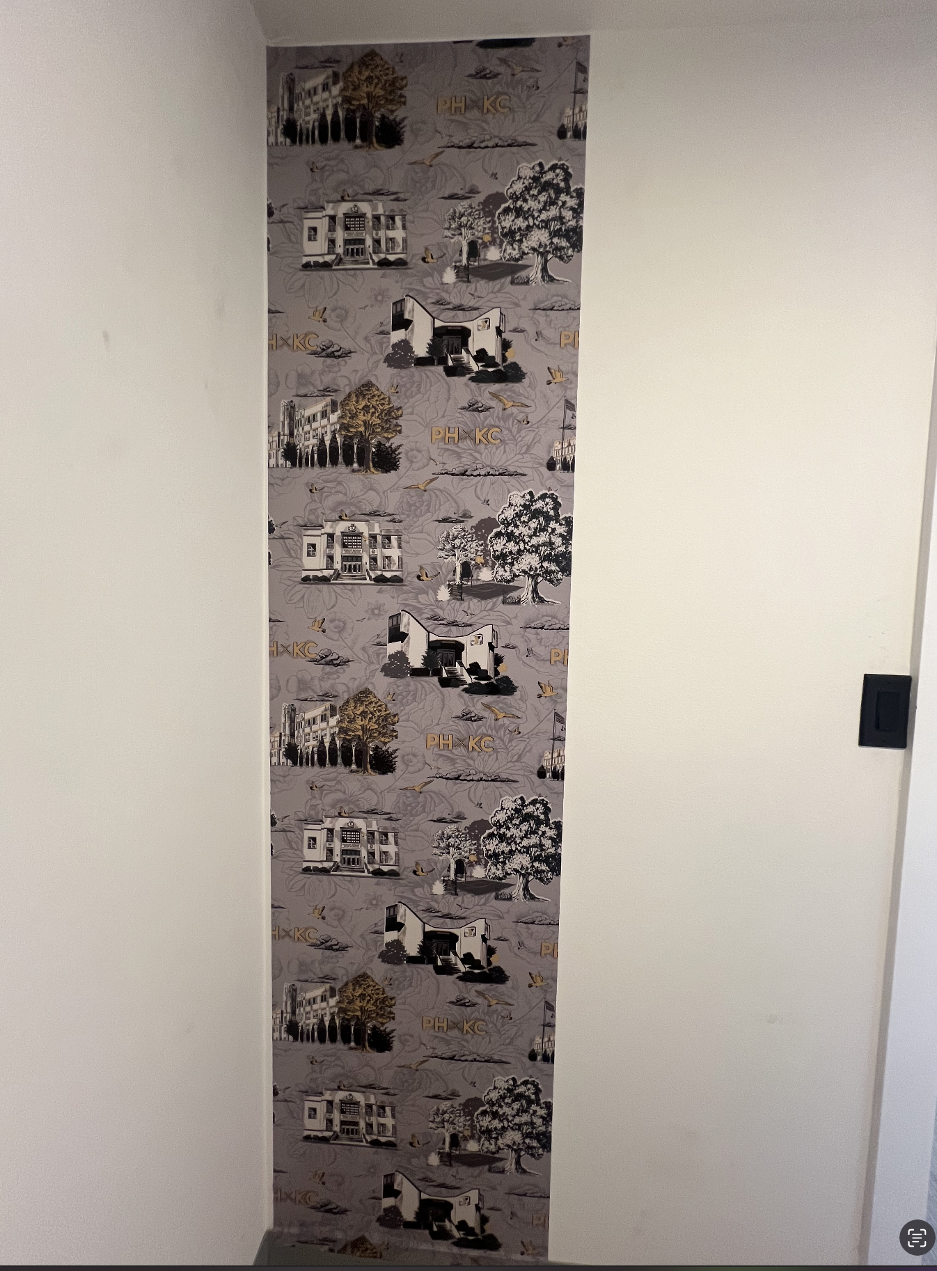 Vertical feature wall installation of the custom Porter House KC toile wallpaper with Kansas City-inspired illustrations and warm neutral tones.