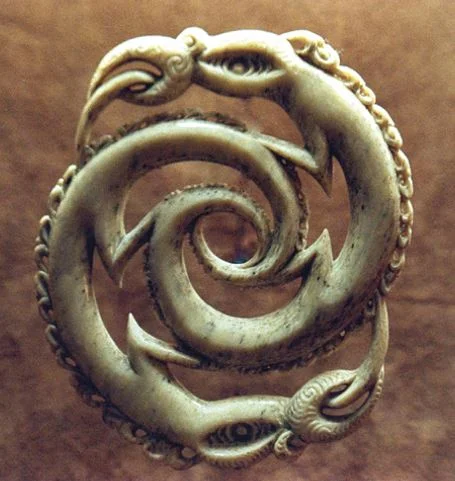 A whalebone carving based on Māori mythology, with the many corresponding ages of Te Ao and Te Pó shown as manaia faces. It was given to the descendants of Pótautau by Ngā Puna Waihanga, the society of Māori Artists and Writers.