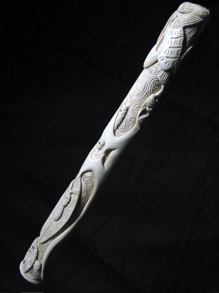 This pōrutu is carved as a kaitiaki of the families of taonga puoro, and it portrays a number of significant traditional beings associated with them, holding tightly to their treasures. It is carved from the leg bone of an ostrich, which was used as…