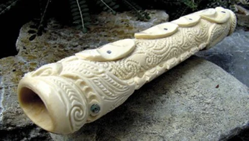 An emu-bone koauau with a carved face 