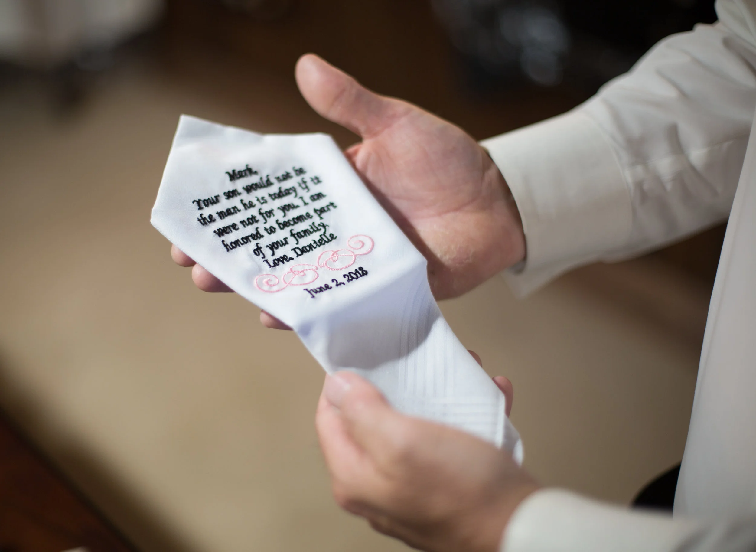 Person holding a white handkerchief with embroidered text.