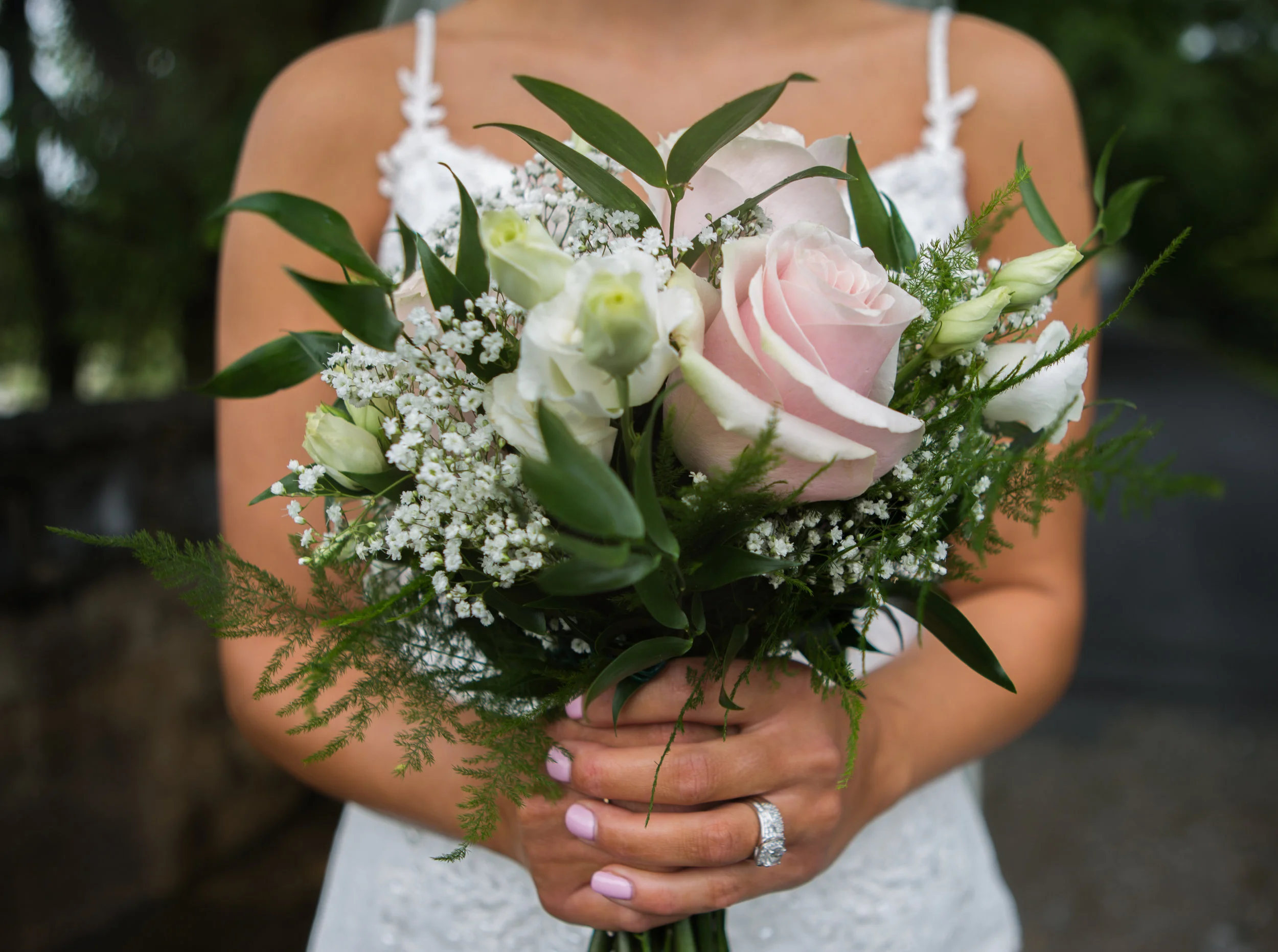 Bride holding bouquet with pink roses, white flowers, and greenery