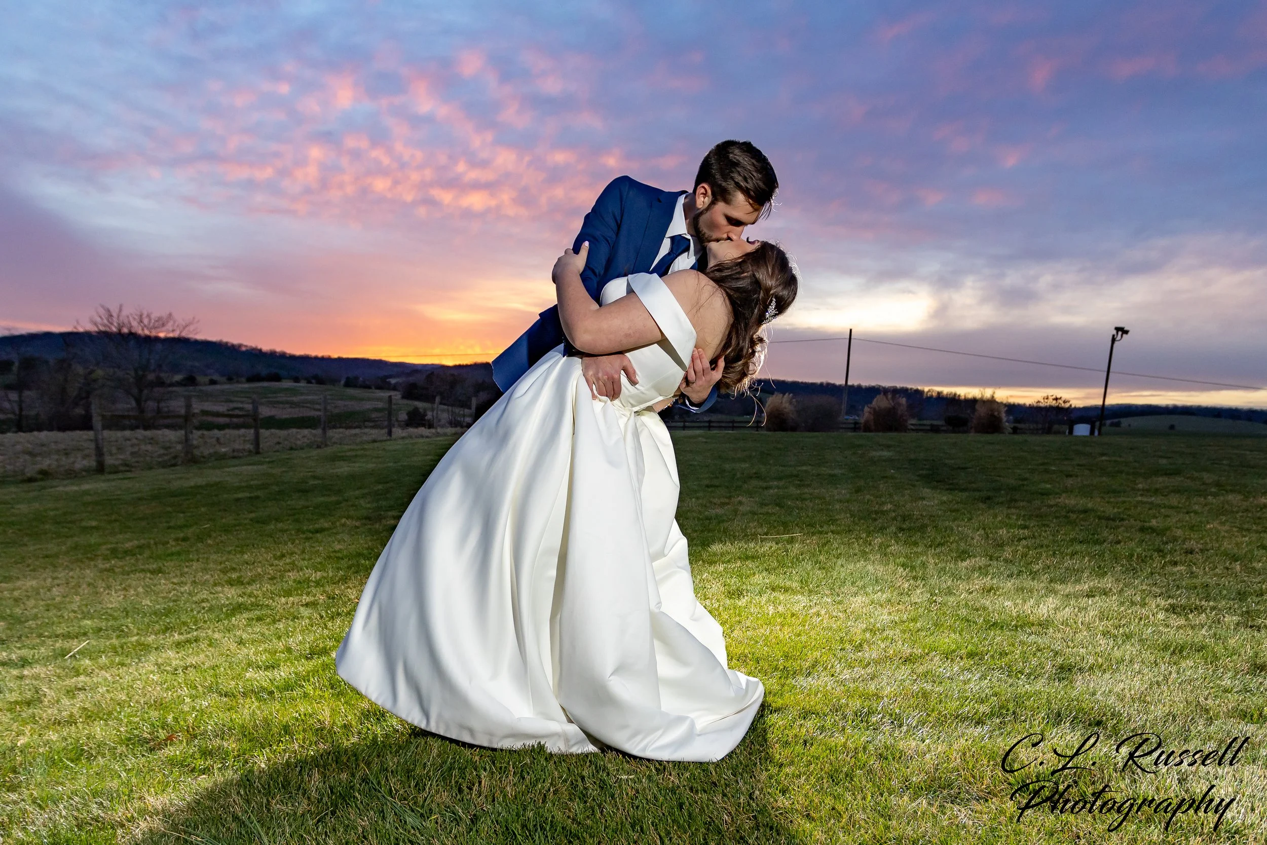 Bride and groom kissing at sunset on a grassy field