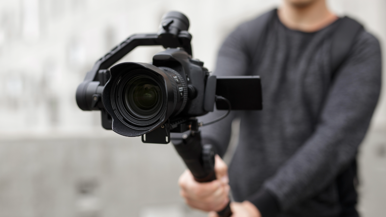 Close-up of a person holding a video camera on a stabilizer.