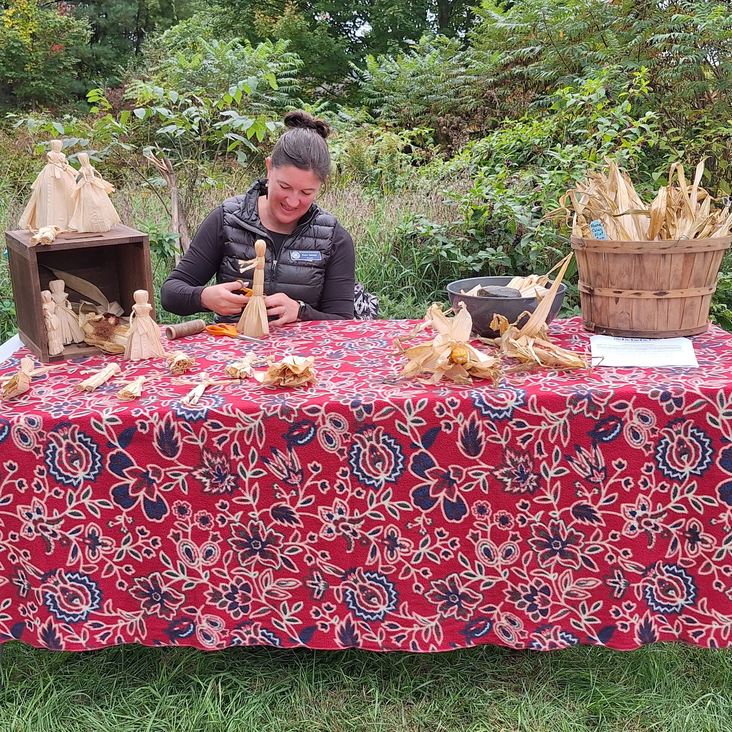 Artist at booth showing how to make native craft using corn leaves