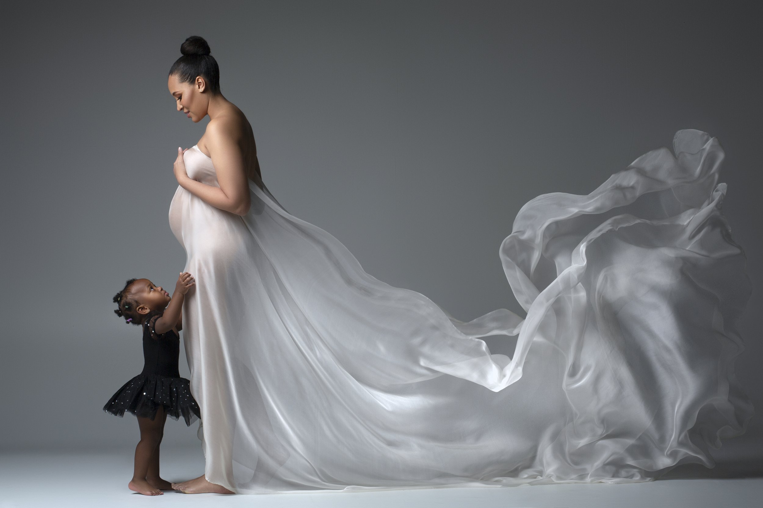 Maternity photo: Woman in white dress surrounded by children