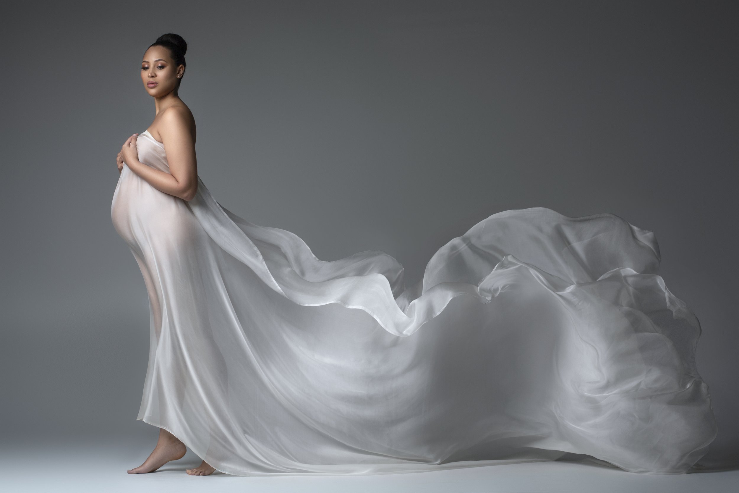 Indoor maternity photoshoot with pregnant woman in white dress