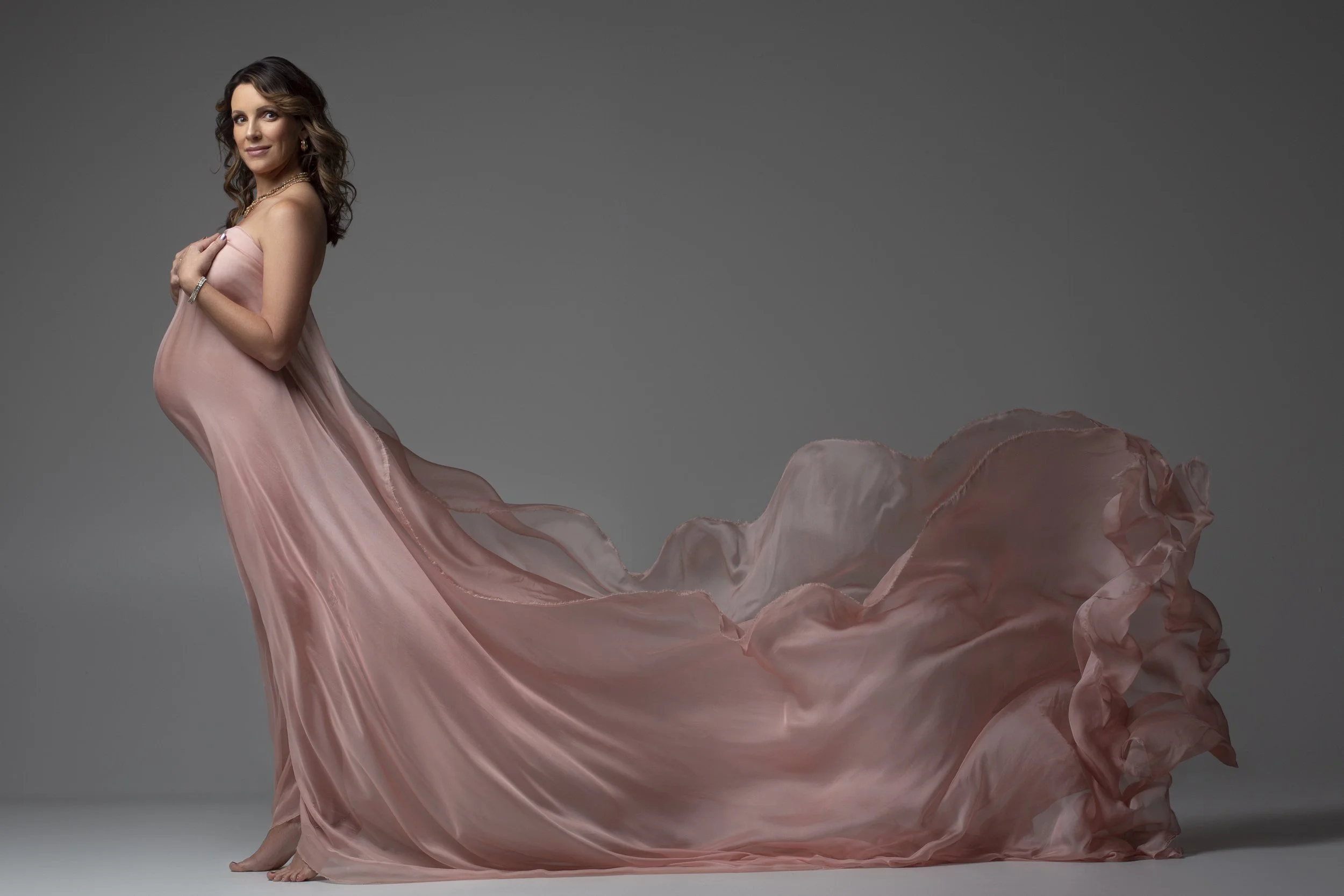 Indoor maternity photoshoot with woman in light pink dress