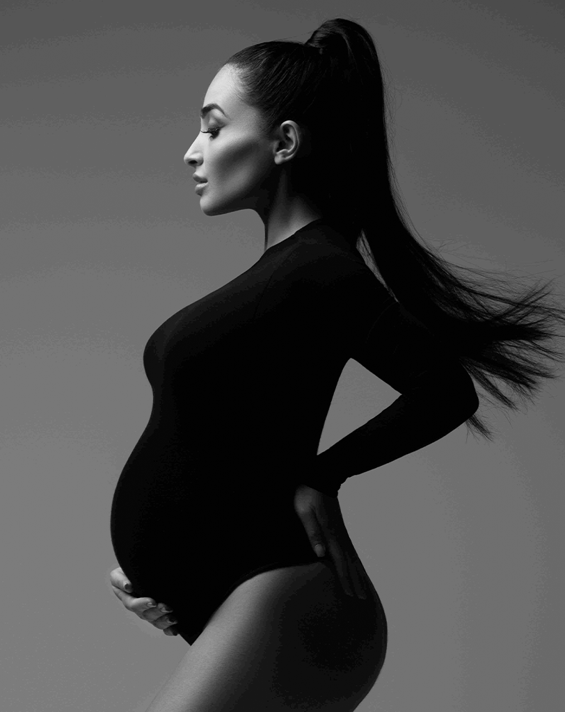 Pregnant lady in a black bodysuit in maternity photography studio