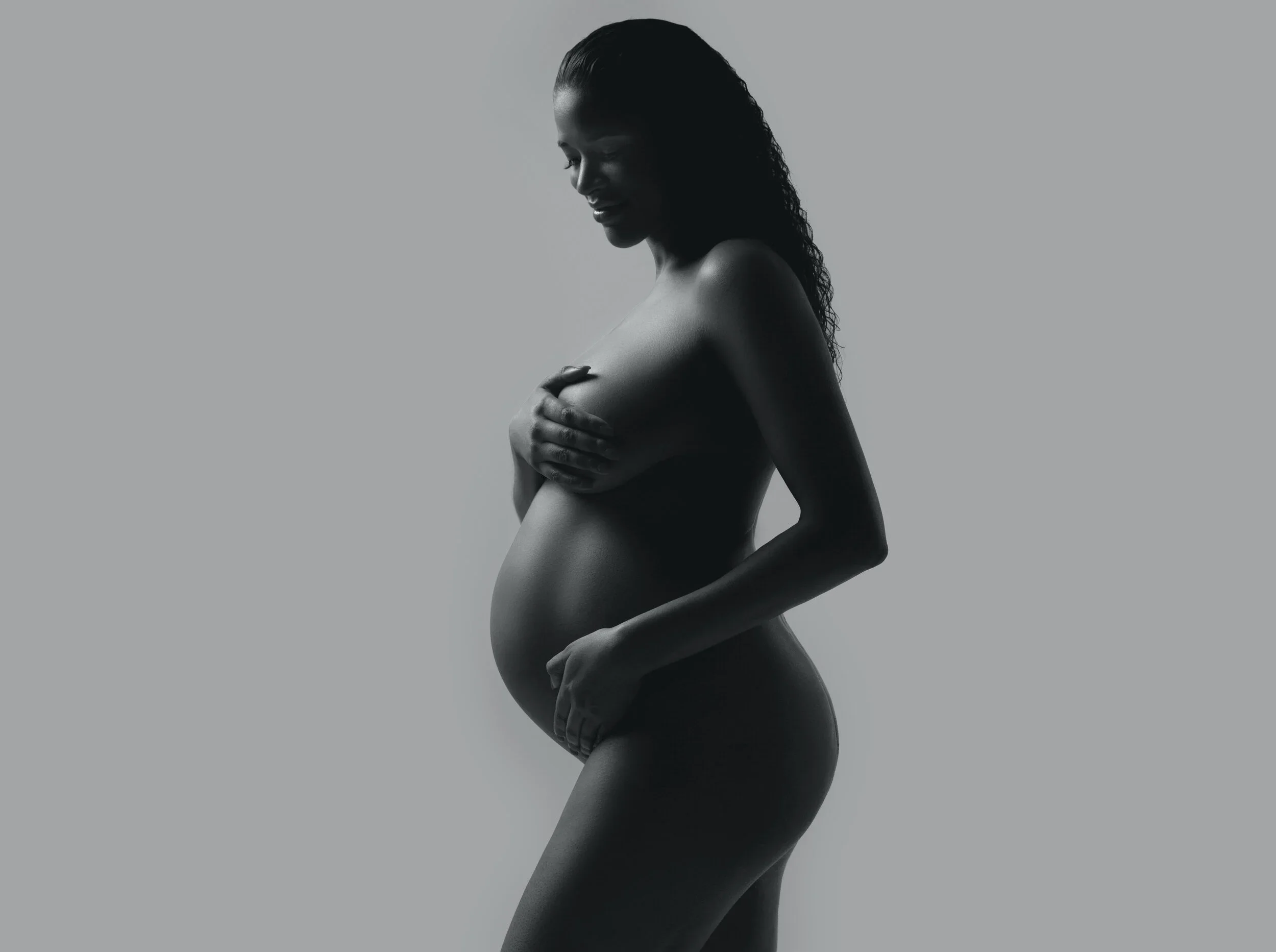 Best Chicago maternity photographer black and white artistic studio portrait of pregnant woman cradling belly