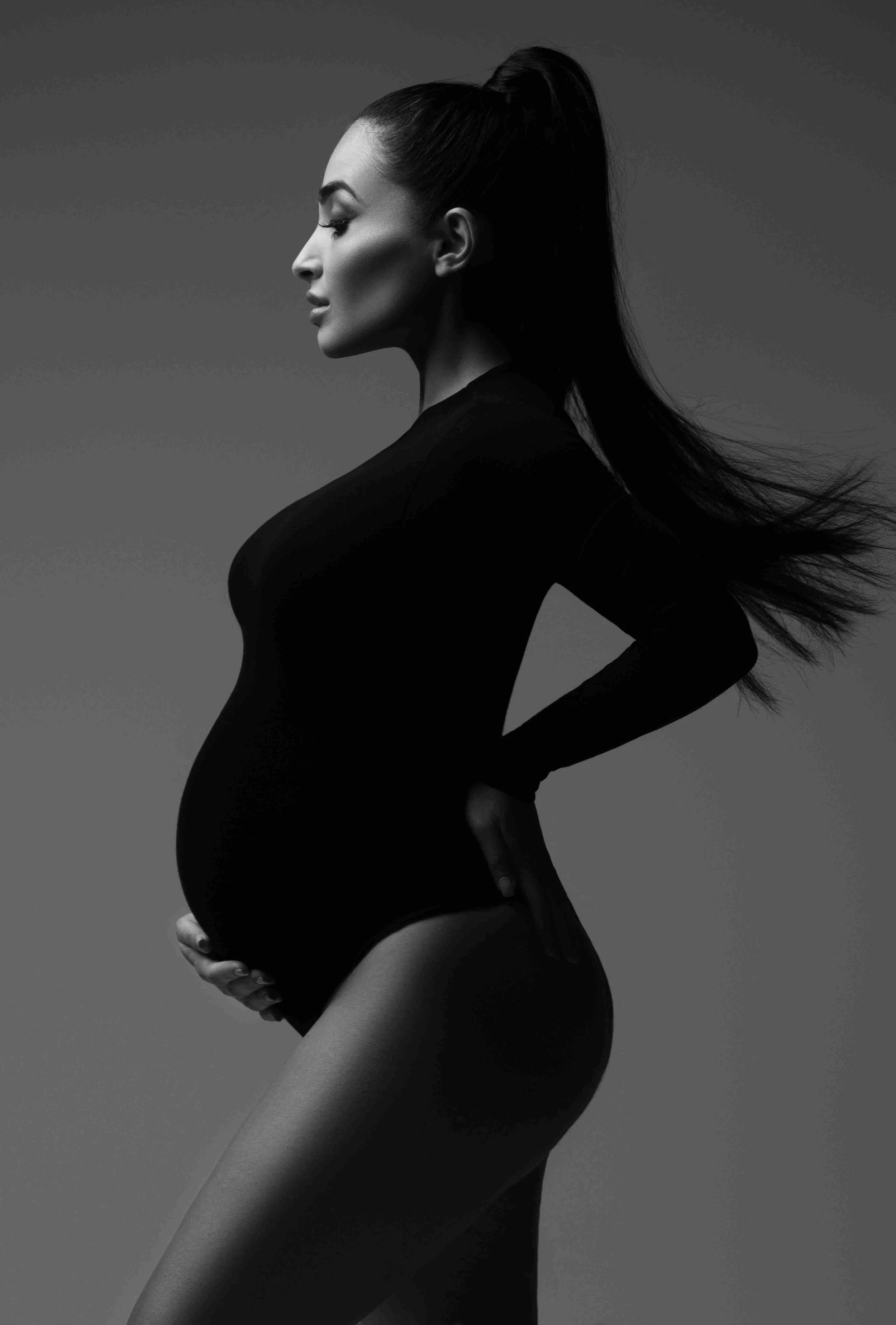 Chicago Maternity Black and white photo of a pregnant woman with long hair wearing a black bodysuit