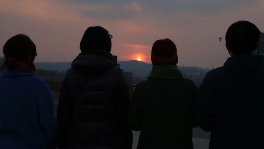 Silhouettes of 4 people looking at a sunset