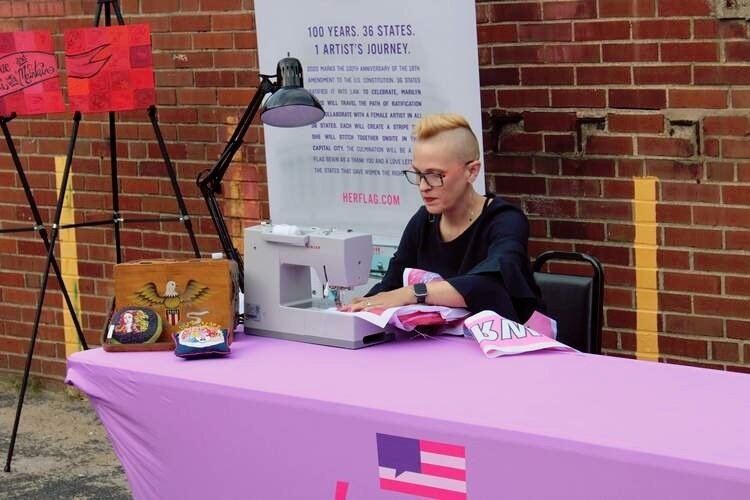  Marilyn Artus, an Oklahoma-based artist, sews a stripe onto a flag in celebration of the 100th anniversary of the 19th Amendment at a ceremony in Des Moines on Saturday, Aug. 24. An artist in Iowa was commissioned to create a stripe representing Iow