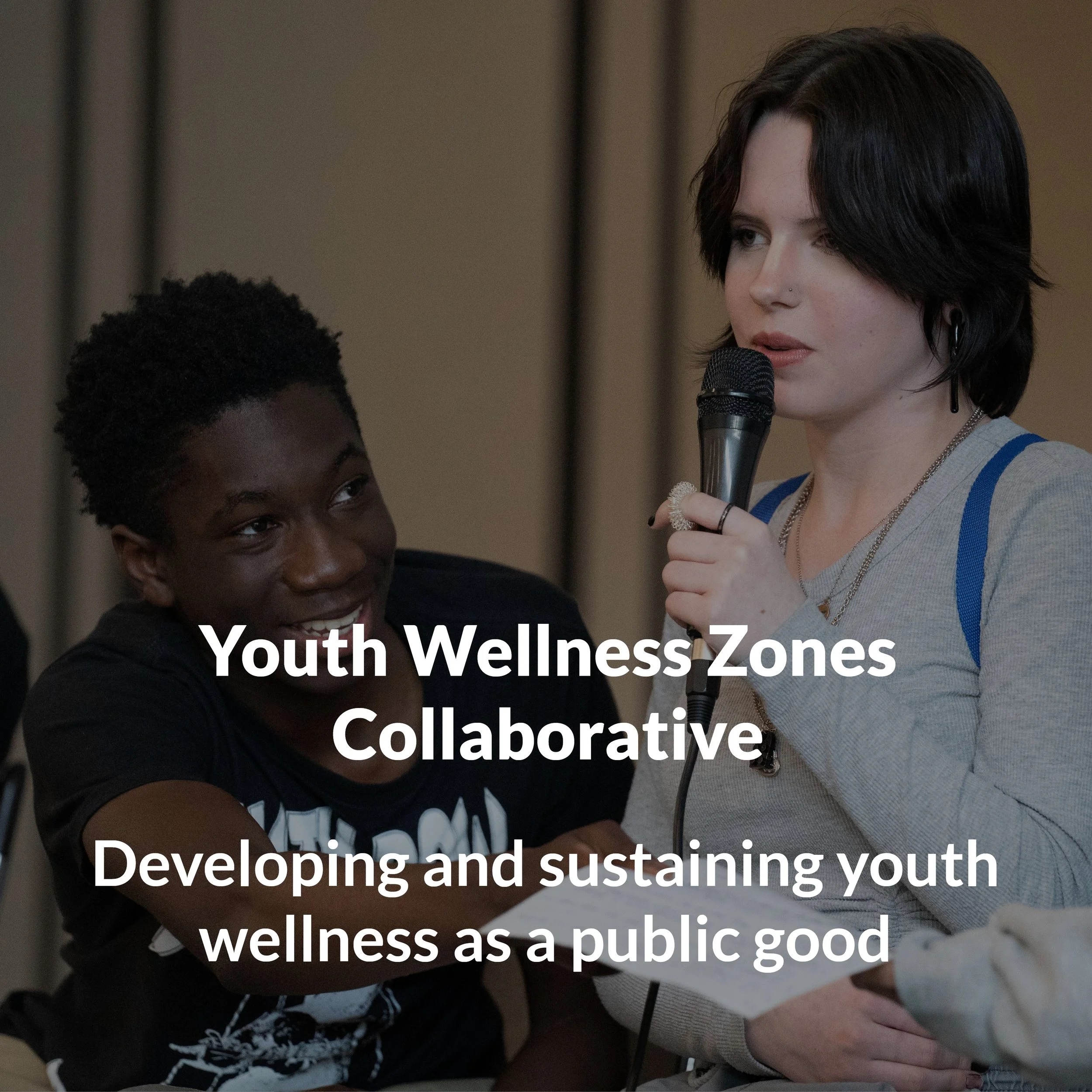 Text reads, " Youth Wellness Zones Collaborative, Developing and Sustaining Youth Wellness as a Public Good". In the background, a Black teenager, onstage, smiles as he passes a paper to someone off screen while the speaker next to him.