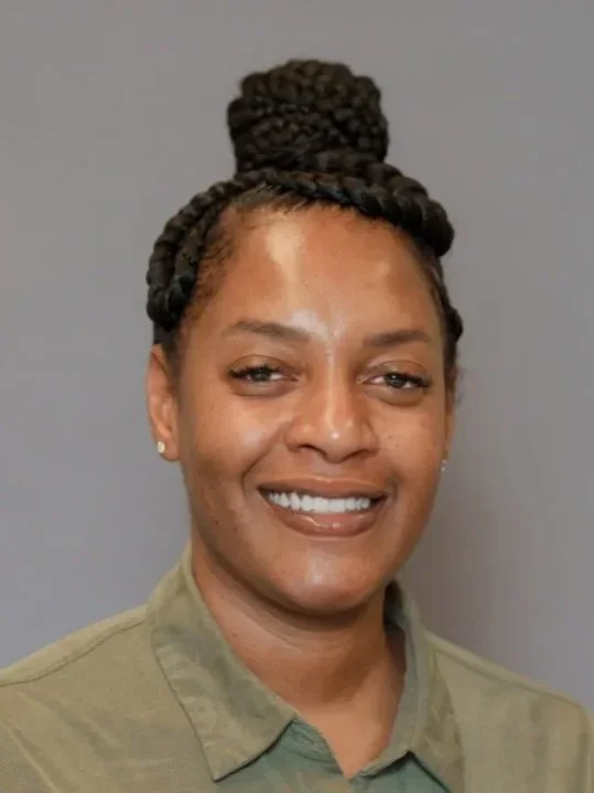 Headshot of Shayla Collins, she is wearing a muted olive green collared shirt as she smiles to the camera.