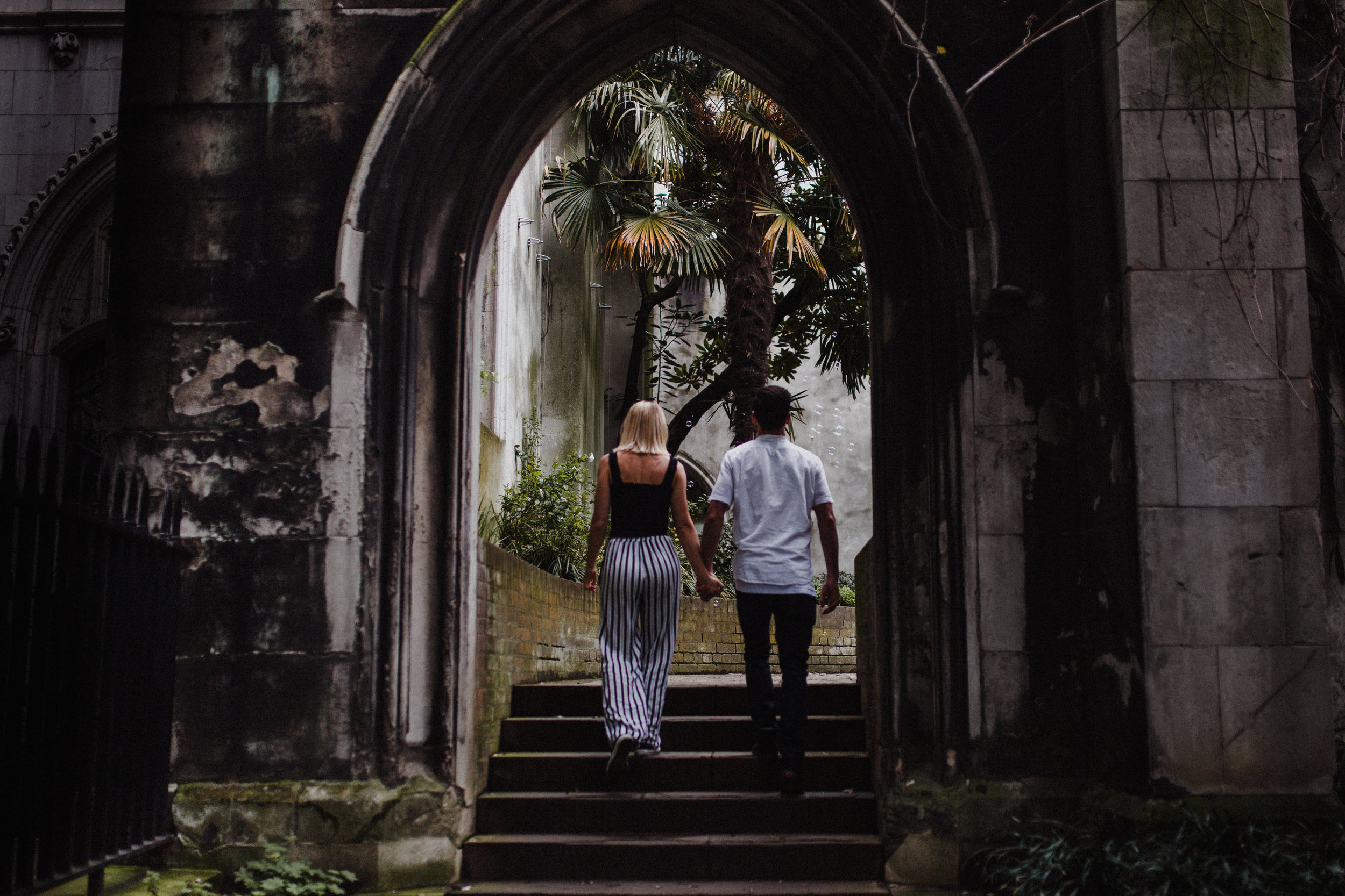 Couple walk hand in hand through the ruins of St Dunstan-in-the-East