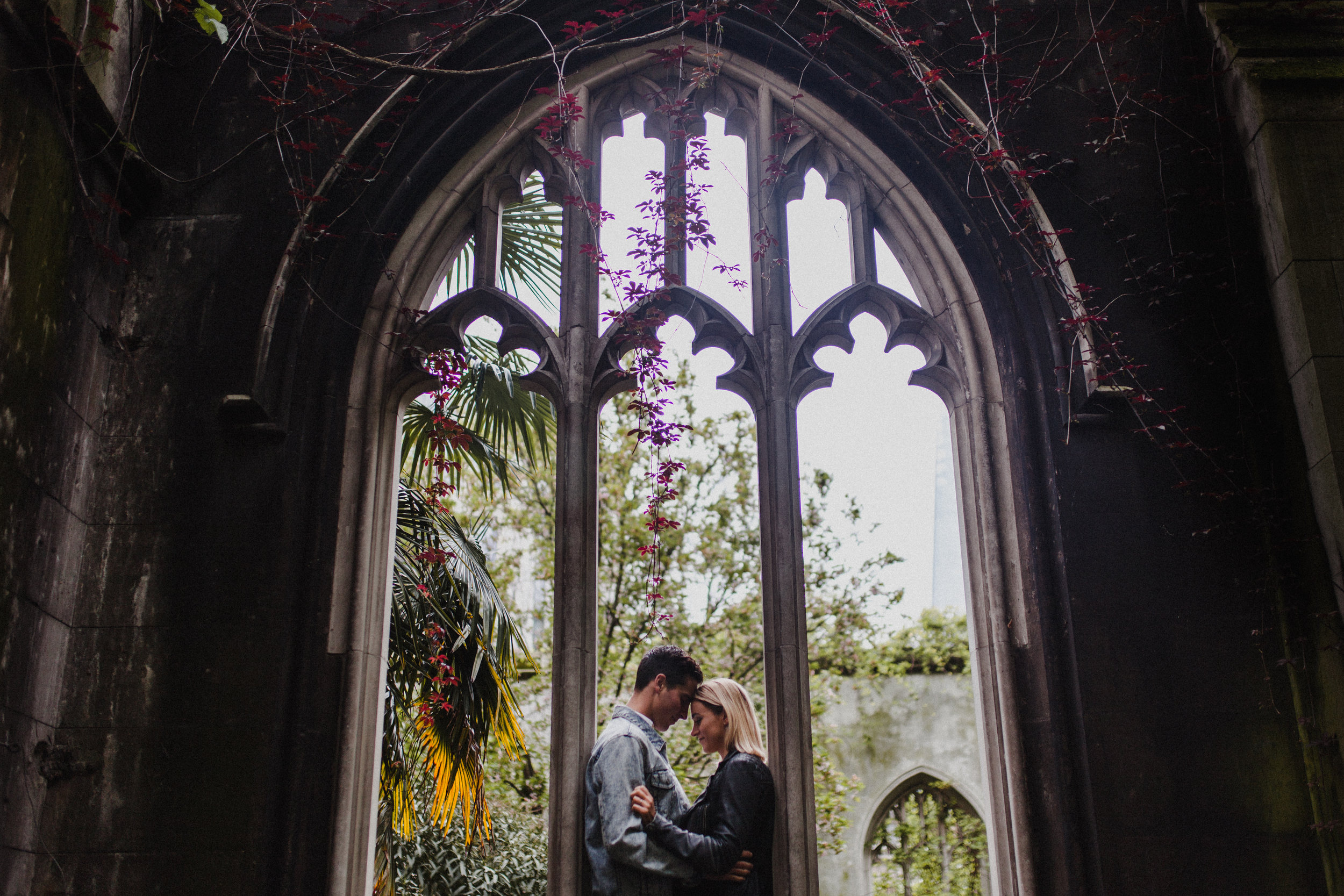 A beautiful stone window frames the couple in this portrait at the gardens at St Dunstan-in-the-East